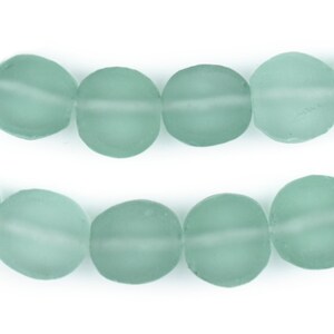 May include: A strand of light blue glass beads. The beads are oval shaped and have a frosted finish.
