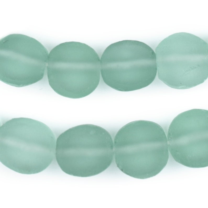 May include: A strand of light blue glass beads. The beads are oval shaped and have a frosted finish.