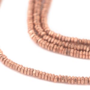 May include: A strand of rose gold hammered beads. The beads are small and have a slightly irregular shape.
