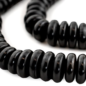 Puede incluir: Una hebra de cuentas negras, redondas y planas. Las cuentas están enhebradas para formar un collar o una pulsera.