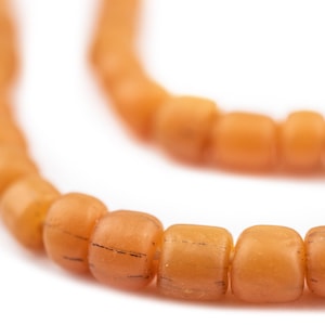 Op de afbeelding: Een close-up van een streng oranje kralen. De kralen zijn rond en hebben een licht getextureerd oppervlak.