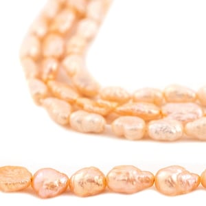 Könnte beinhalten: Eine Kette aus hellrosa Süßwasserperlen mit barocker Form auf weißem Hintergrund.