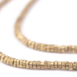 Puede incluir: Una cadena de color dorado hecha de pequeñas cuentas redondas. Las cuentas tienen una superficie texturizada y están dispuestas en una línea continua.
