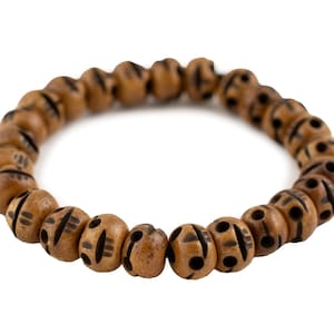 Op de afbeelding: Een houten kralenarmband met een natuurlijke afwerking. De ronde kralen hebben geëtste zwarte ontwerpen. De armband is aan elkaar geregen, waardoor een flexibel accessoire ontstaat. Geschikt voor dagelijks gebruik, het is een eenvoudig ontwerp.