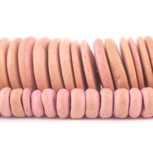 Può includere: Primo piano di due fili di perline di legno rosa. Il filo superiore presenta perline piatte a forma di disco, mentre il filo inferiore ha perline rettangolari arrotondate. Le perline sono di un rosa tenue e lo sfondo è bianco.