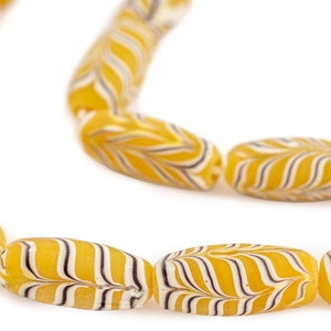 May include: A strand of yellow glass beads with white and black swirl patterns. The beads are oval shaped and strung together to form a necklace.