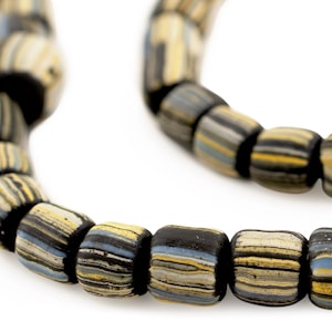 Puede incluir: Primer plano de un collar de cuentas cilíndricas a rayas negras, amarillas, azules y crema. Las cuentas están ensartadas, creando un collar o pulsera. Cada cuenta mide aproximadamente 1 cm de largo.