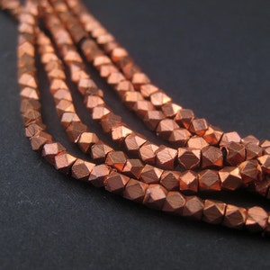 May include: A strand of copper-coloured faceted beads. The beads are small and have a metallic sheen.