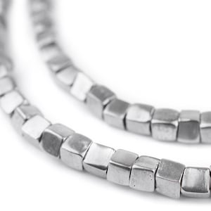 Puede incluir: Un collar de plata hecho de cuentas cuadradas. Las cuentas están unidas para formar una cadena.
