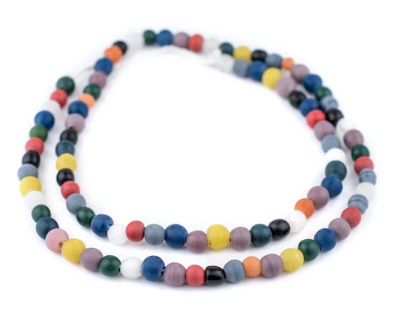 Puede incluir: Dos hilos de collares de cuentas de colores. Las cuentas son redondas y vienen en una variedad de colores, incluyendo rojo, azul, verde, amarillo y blanco. Los collares se muestran sobre un fondo blanco.