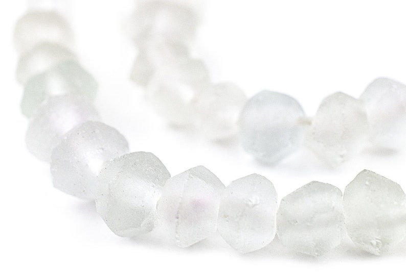 May include: A strand of white glass beads with a frosted finish. The beads are faceted and have a slightly iridescent sheen.