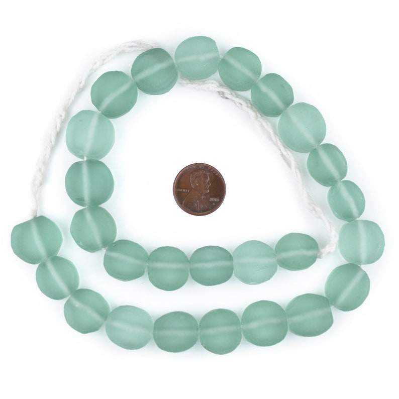 May include: A strand of light green glass beads, approximately the size of a US penny, strung on a white cord.