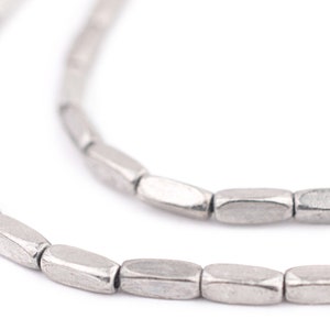 May include: A silver chain necklace made of small, rectangular beads with a hammered texture.