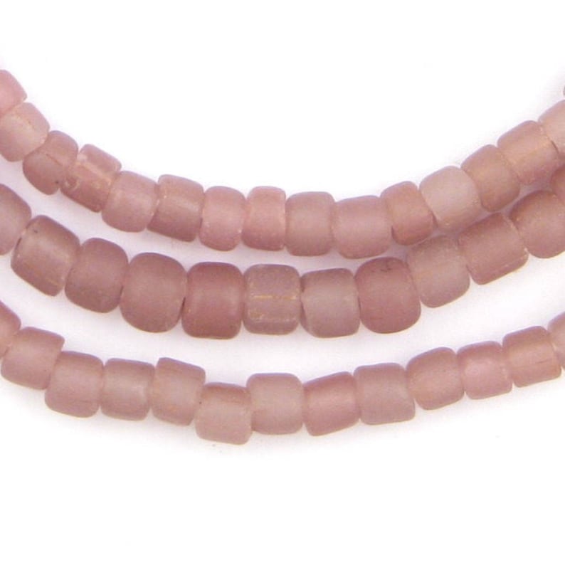 May include: A strand of light pink glass beads. The beads are small and round, with a matte finish.