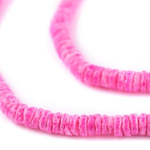 May include: A strand of pink shell beads, strung together to form a necklace or bracelet. The beads are small and round, with a slightly textured surface.