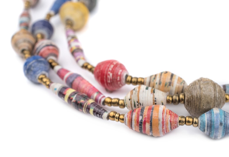 May include: A colorful necklace made of rolled paper beads. The beads are in various colors, including red, blue, yellow, and green. The beads are strung on a gold cord.