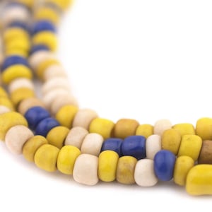 May include: A close-up of a multi-strand necklace made of yellow, white and blue beads. The beads are arranged in a repeating pattern.