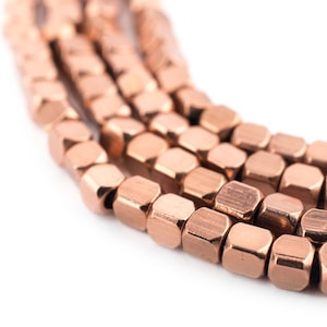 May include: A strand of copper-colored beads, each bead is a hexagonal shape with a slightly textured surface.