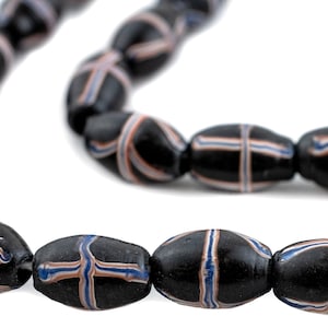 May include: A strand of black glass beads with white and blue stripes. The beads are oval shaped and have a glossy finish.