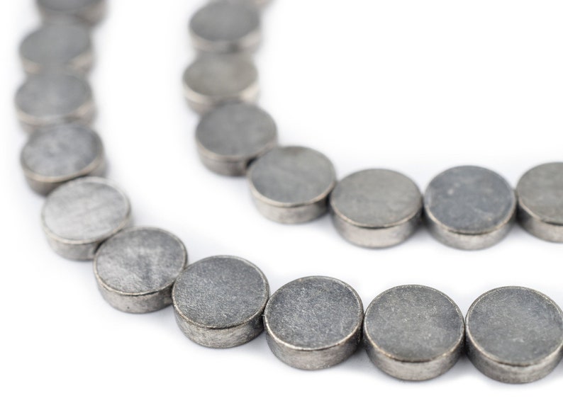 Pu&ograve; includere: Una collana di perline rotonde color argento. Le perline sono lisce e hanno una superficie leggermente ruvida.