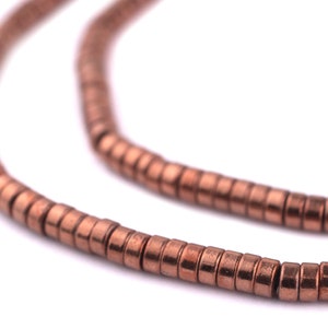 May include: A strand of copper-colored beads, each bead is a small cylinder with a slightly textured surface.