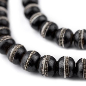 May include: A black beaded necklace with silver accents. The beads are round and have a smooth, polished finish.