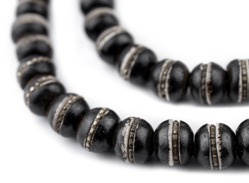 May include: A black beaded necklace with silver accents. The beads are round and have a smooth, polished finish.