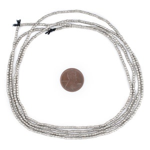 May include: A strand of silver-toned beads, approximately the size of a US penny, arranged in a circle on a white background.