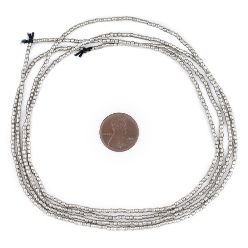 May include: A strand of silver-toned beads, approximately the size of a US penny, arranged in a circle on a white background.
