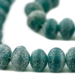 May include: A necklace or bracelet featuring teal-coloured, oval beads with a textured, frosted finish. The beads are strung together, and the image is set against a white backdrop. Each bead is approximately 1 cm in diameter.