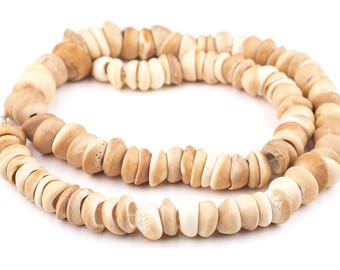 Op de afbeelding: Een ketting gemaakt van natuurlijke beige en bruine schelp kralen. De kralen zijn aan elkaar geregen op een dun koord en zijn van verschillende groottes en vormen.