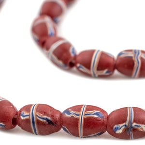 Op de afbeelding: Snoer van rode, ovale kralen met witte, blauwe en bruine streepmotieven. De kralen zijn aan elkaar geregen en vormen een gebogen lijn tegen een witte achtergrond. De kralen hebben een licht matte afwerking.
