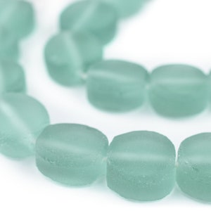 May include: A strand of light blue glass beads, each bead is oval shaped and frosted.