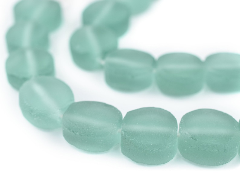 May include: A strand of light blue glass beads, each bead is oval shaped and frosted.