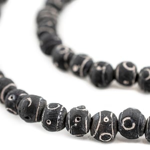 May include: A black beaded necklace with white circular patterns on each bead.