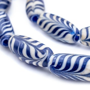 Könnte beinhalten: Nahaufnahme einer Schnur aus blauen und weißen Glasperlen. Die Perlen sind oval geformt und haben ein wirbelndes Muster.