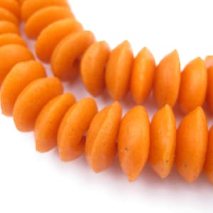 Puede incluir: Primer plano de una cadena de cuentas naranjas. Las cuentas están hechas de un material liso y redondo y están enhebradas en un bucle continuo.
