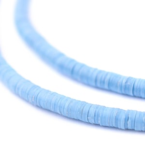 May include: Close-up of two strands of light blue disc-shaped beads. The beads are strung together, creating a necklace or bracelet. The beads have a slightly textured surface and are a soft, pastel blue color.