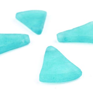 May include: Four pieces of sea glass in a light turquoise color are arranged on a white background. The pieces have smooth, rounded edges and a slightly frosted appearance, suggesting they have been tumbled by the ocean.