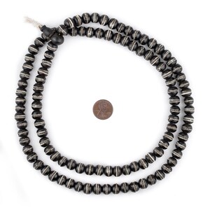 May include: A black and white beaded necklace with a tassel. The beads are round and have a white stripe around the middle. The necklace is about 18 inches long.
