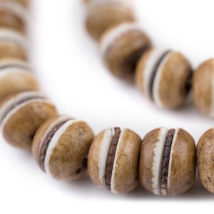 May include: A brown wooden beaded necklace with white and copper accents. The beads are round and have a smooth finish.