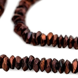 Peut inclure: Gros plan sur deux rangées de perles marron foncé à facettes. Les perles ont un éclat métallique et une forme irrégulière. Les perles sont enfilées ensemble, créant un collier ou un bracelet.