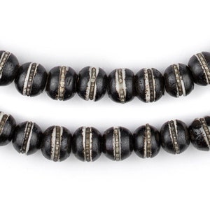 May include: A strand of black wooden beads with white accents. The beads are round and have a smooth, polished finish.