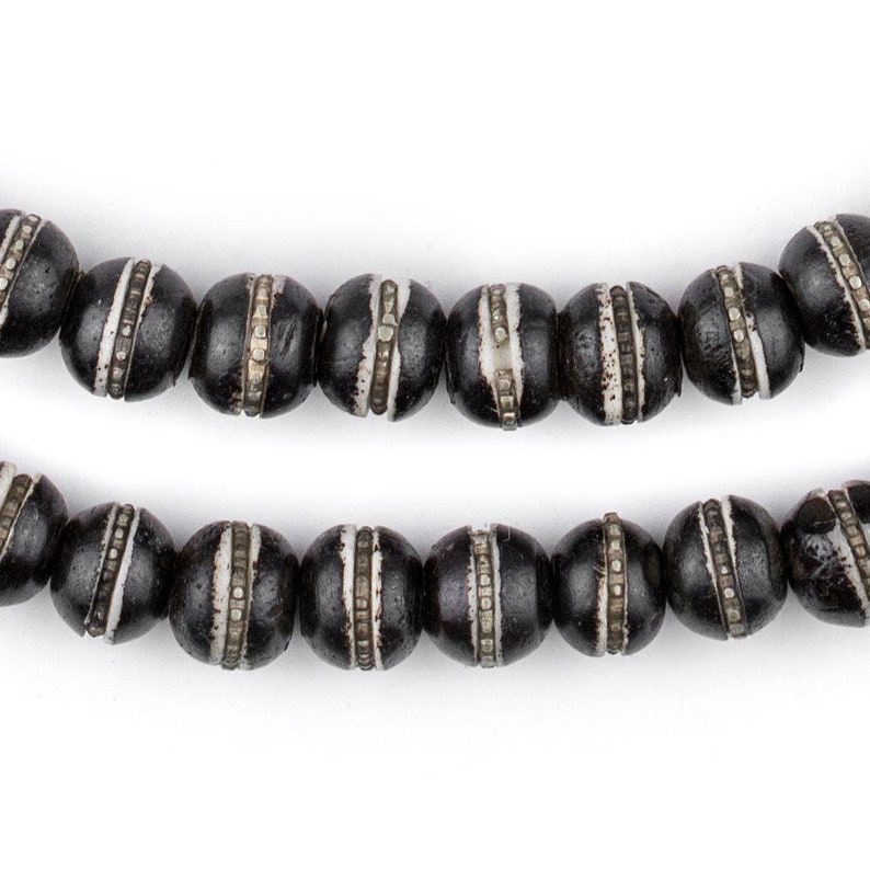 May include: A strand of black wooden beads with white accents. The beads are round and have a smooth, polished finish.