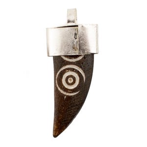 May include: A pendant featuring a dark brown, tooth-shaped charm with a silver-colored metal cap and bail. The charm has a carved spiral design in white. The pendant is likely for a necklace or other jewelry.