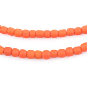 Könnte beinhalten: Eine Strähne aus leuchtend orangefarbenen Glasperlen. Die Perlen sind rund und haben eine leicht matte Oberfläche.