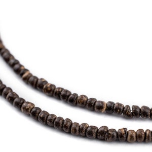 Op de afbeelding: Een close-up van een bruine houten kralenketting. De kralen zijn klein en rond, en de ketting is gemaakt van twee strengen.