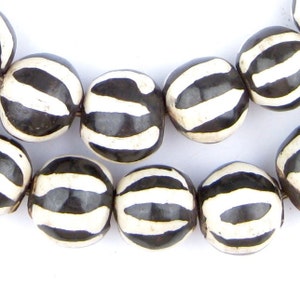 May include: A strand of black and white striped beads. The beads are round and have a glossy finish.