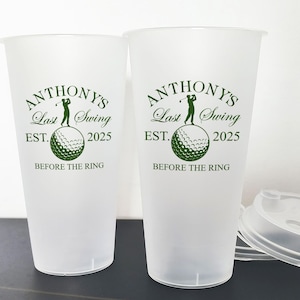 May include: Two white plastic cups with green text and a golf ball graphic. The text reads "Anthony's Last Swing Est. 2025 Before the Ring".