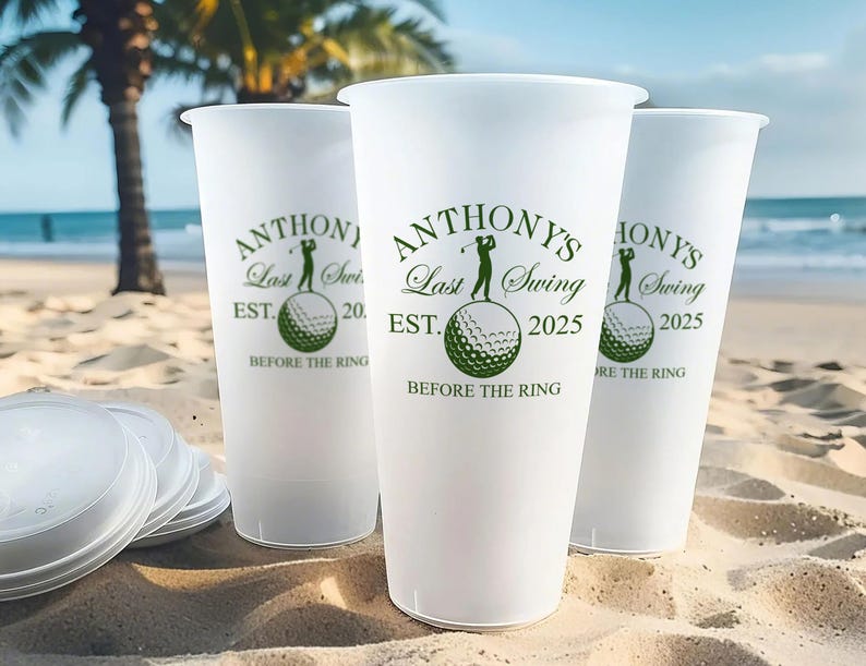 May include: Three white plastic cups with green text and a golf ball graphic. The text on the cups reads "Anthony's Last Swing Est. 2025 Before the Ring".